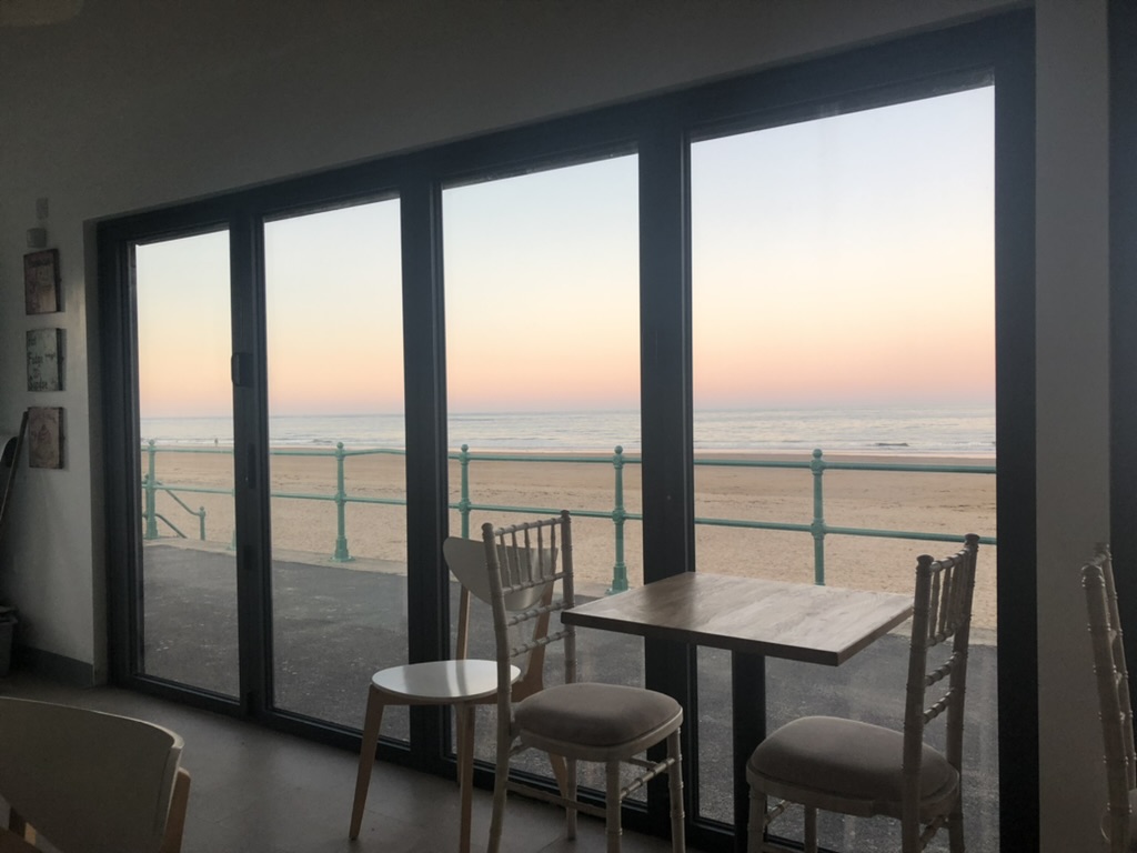 The beach and sea seen through the windows at Strollers Coffee